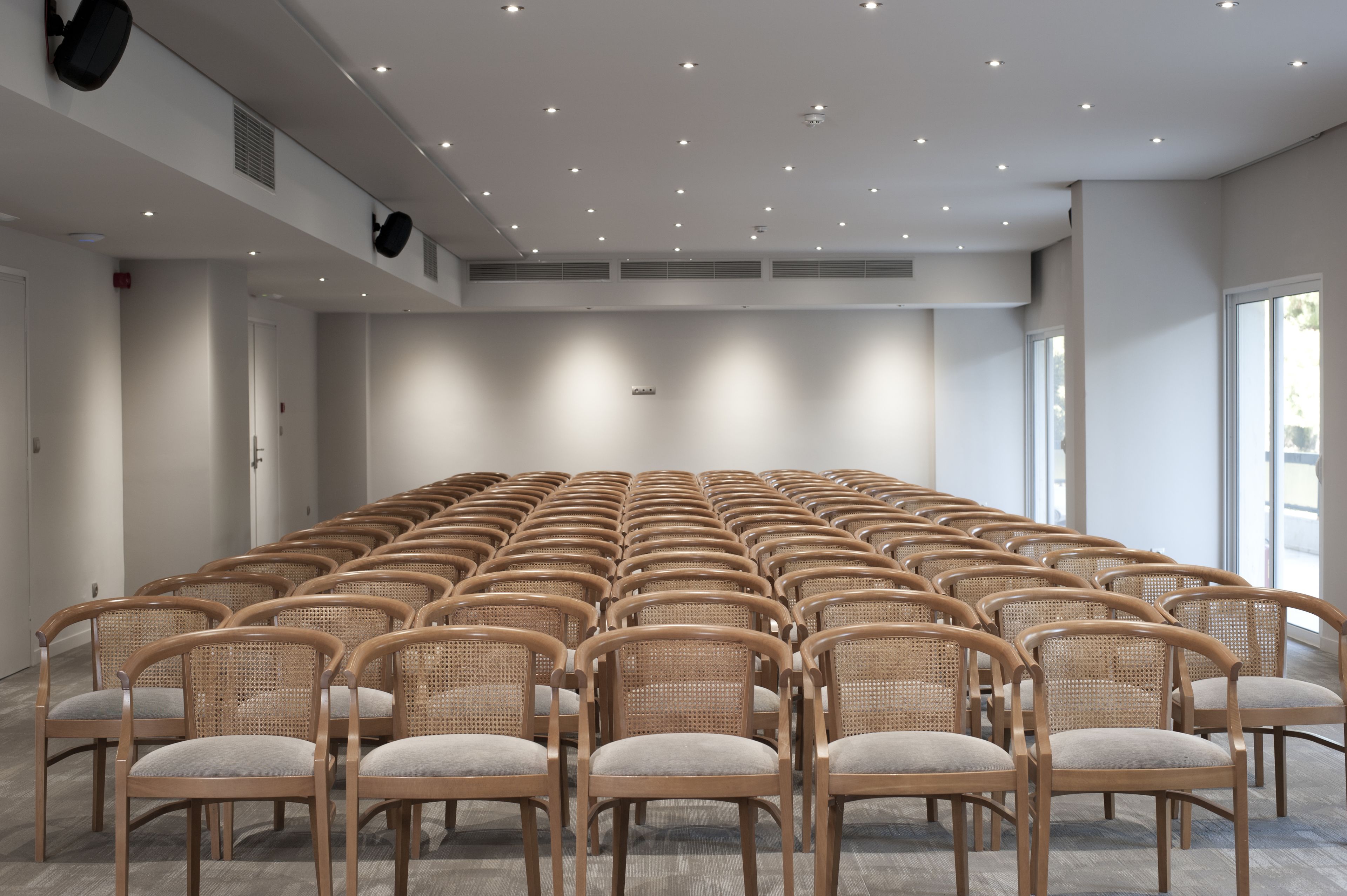 A conference room with rows of wicker chairs and a large whiteboard.