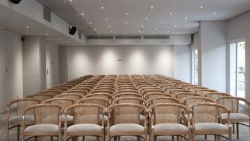 A conference room with rows of wicker chairs and a large whiteboard.