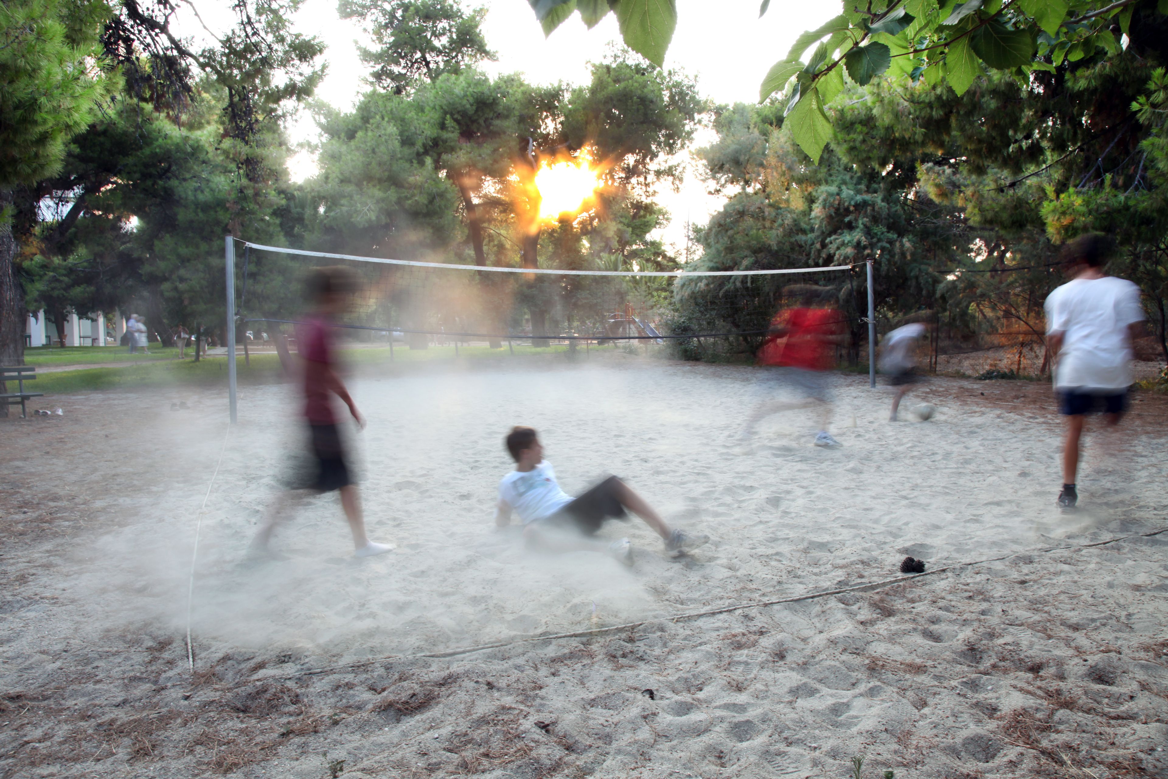 A sandy volleyball court with players and a net.