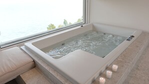Un baño moderno con una bañera grande, un banco y velas.