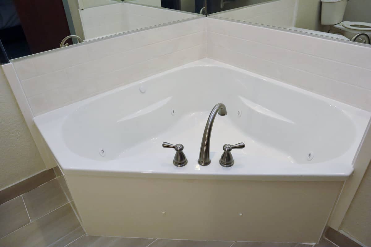 A modern bathroom with a freestanding bathtub, a large mirror, and a toilet.