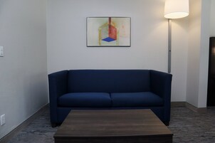 Una habitación con un sofá azul oscuro, una mesa de centro de madera y un cuadro en la pared.