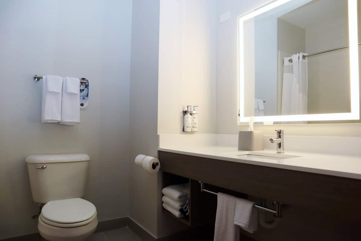 A modern bathroom with a toilet, a sink with a mirror, and a towel rack.