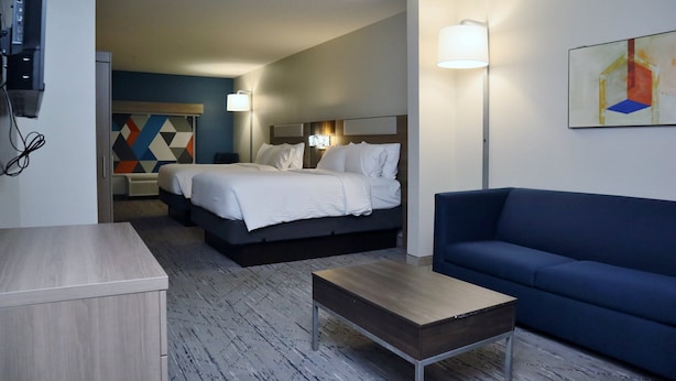 Habitació d'hotel amb un llit, un sofà blau, una taula de centre de fusta i un quadre a la paret.