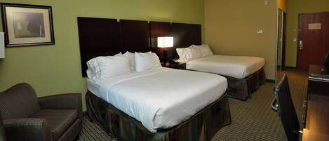A hotel room with two beds, a chair, a desk, and a lamp.