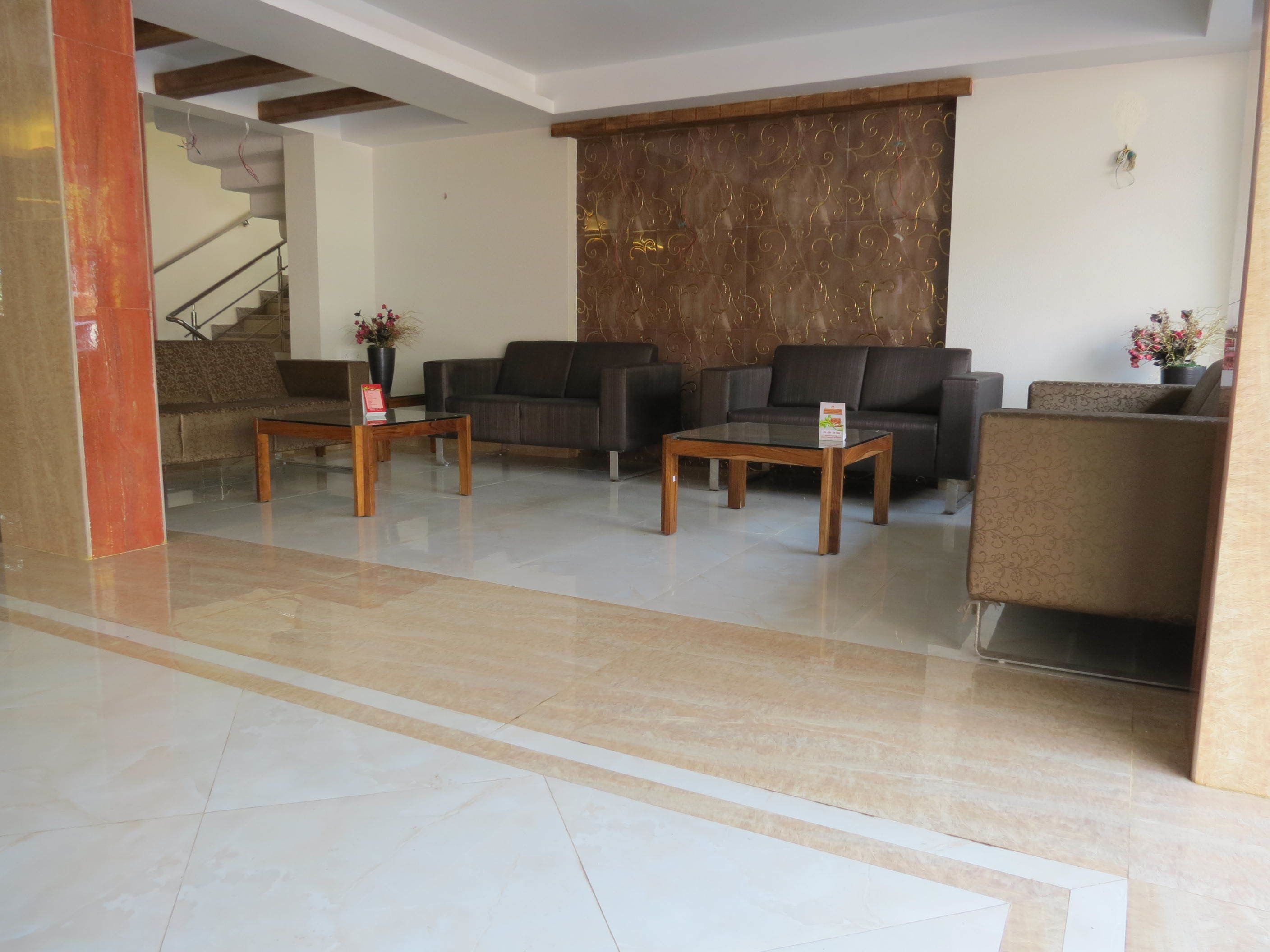 A lobby with a marble floor, two sofas, a coffee table, and a staircase in the background.
