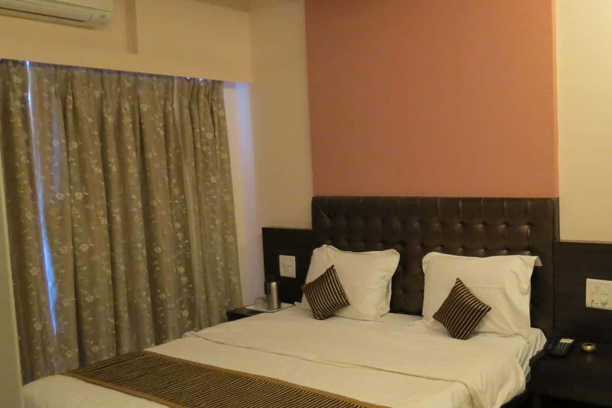 A hotel room with a bed, a nightstand, a telephone, and a ceiling fan.