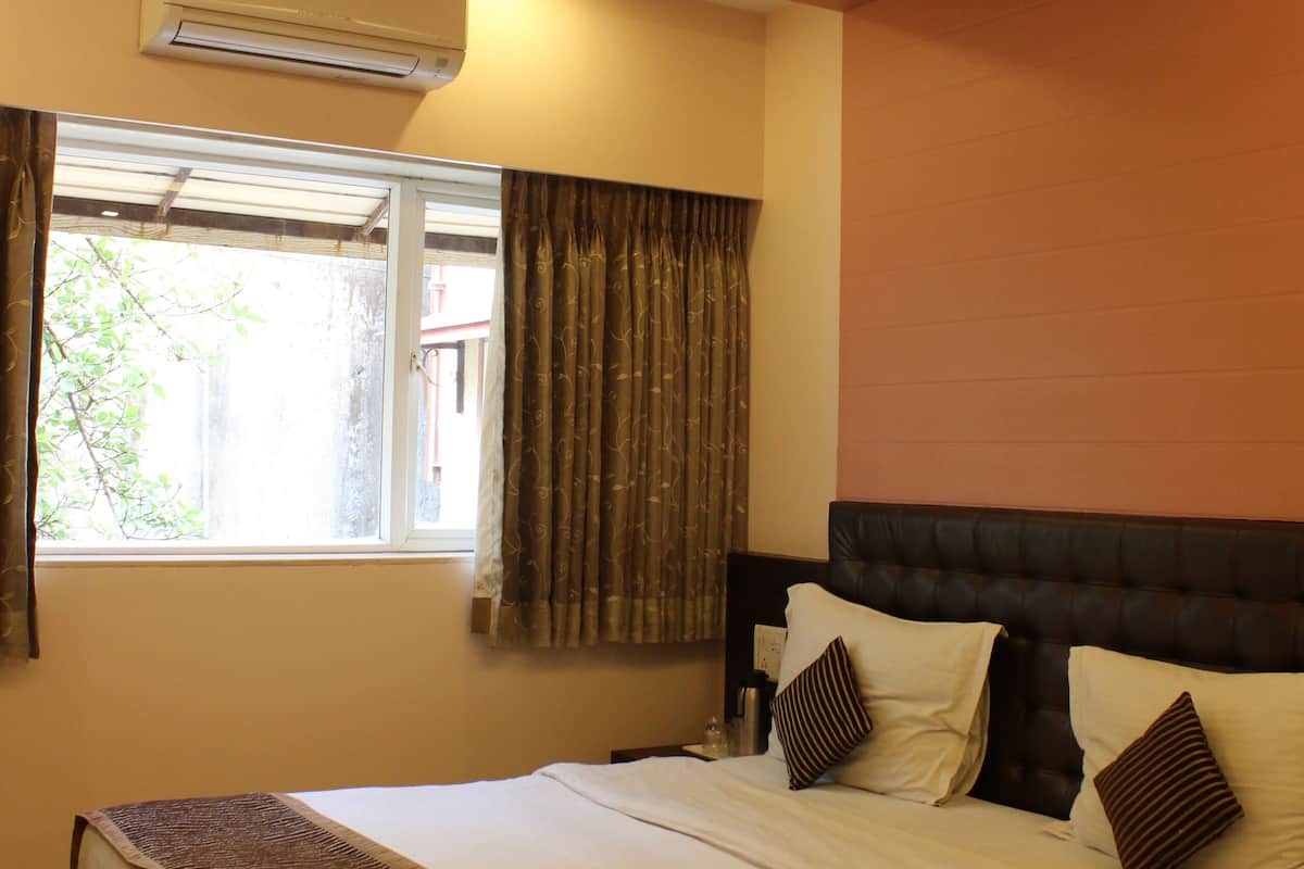A bedroom with a bed, a ceiling fan, an air conditioning unit, and a window with curtains.