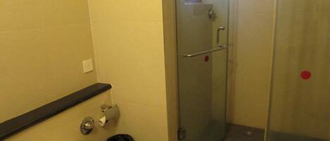 Un baño con inodoro, ducha y puerta de cristal.