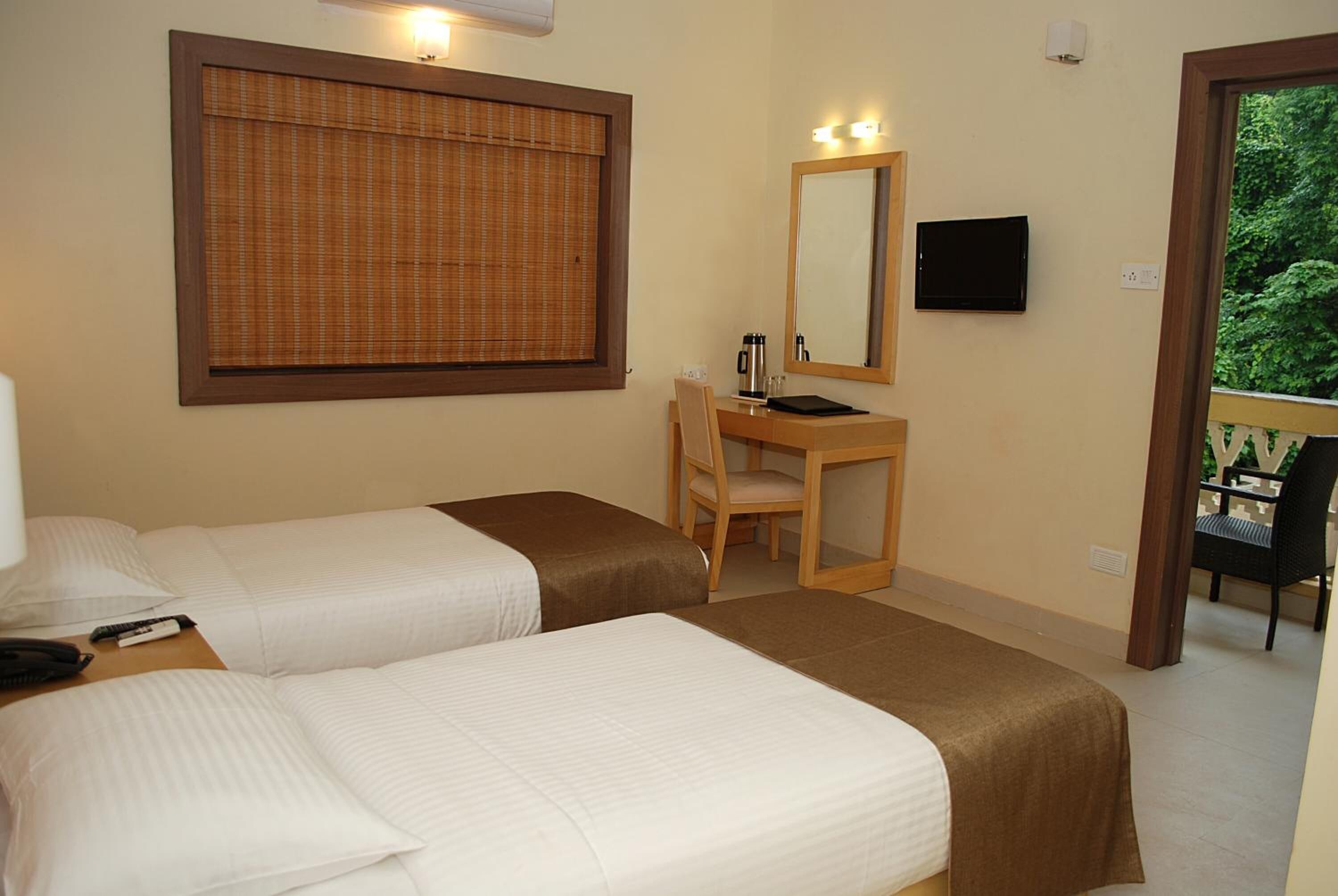 A hotel room with two beds, a desk, a chair, a television, and a window with blinds.