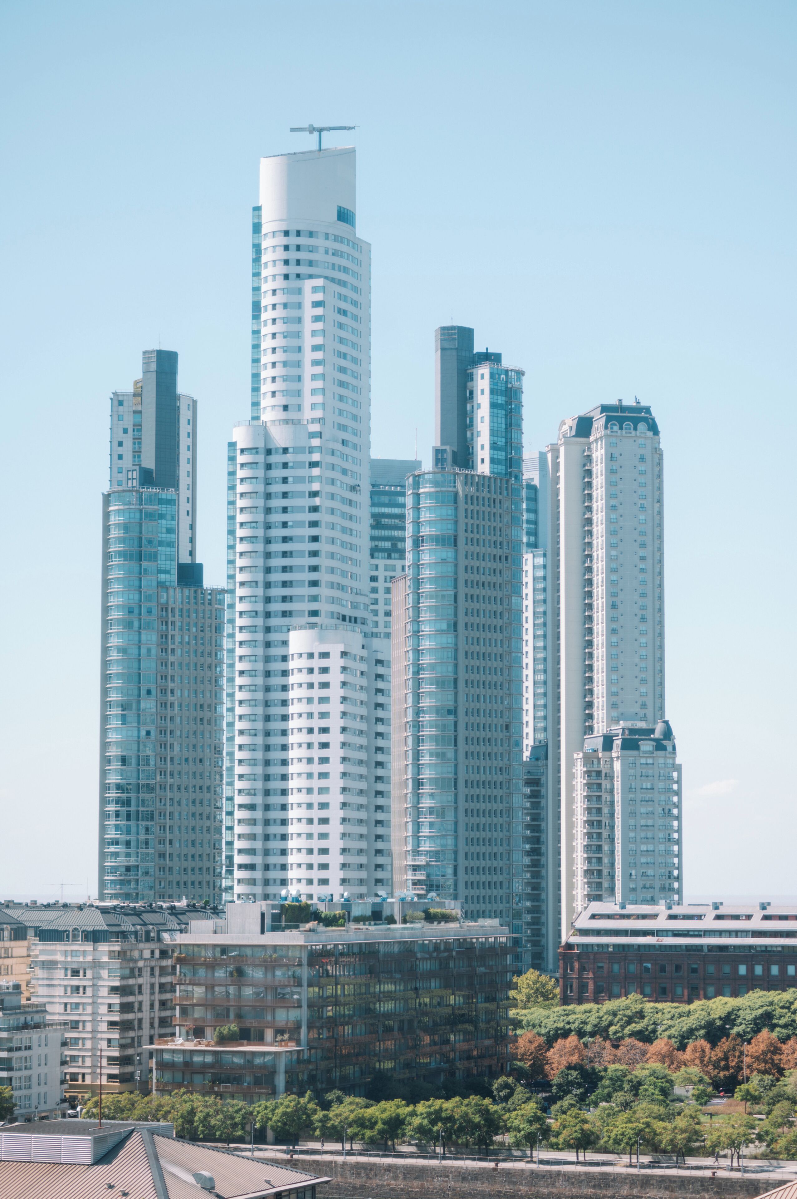 Un paysage urbain avec de nombreux immeubles de grande hauteur, dont un gratte-ciel cylindrique imposant et plusieurs bâtiments rectangulaires.