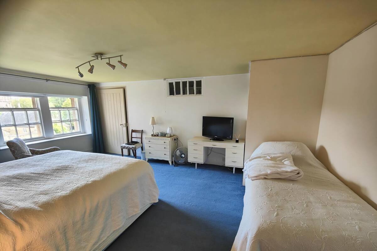 A hotel room with two beds, a desk with a TV, a chair, and a window with a view.