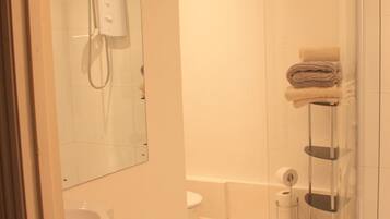 Un baño con cabina de ducha de vidrio, inodoro, lavabo y un perchero para toallas.