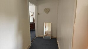 A narrow hallway with a dark carpet, white walls, and a heart-shaped clock on the wall. - Manor Farm Bed & Breakfast (Chippenham)