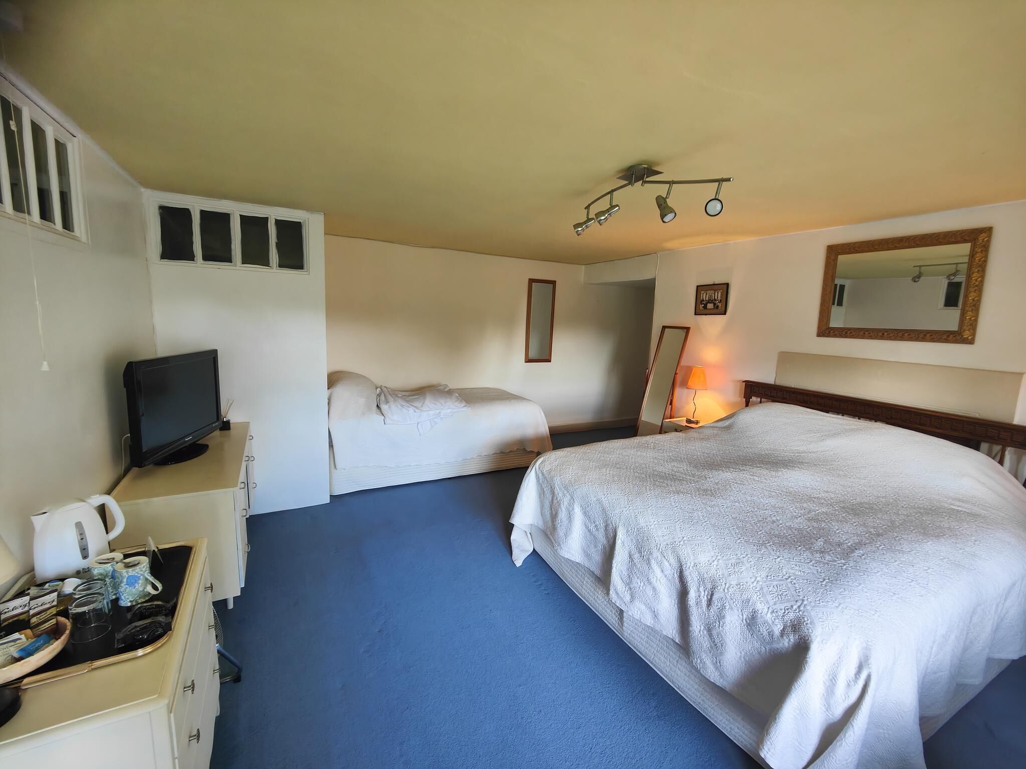 Une chambre d’hôtel équipée d’un lit, d’une télévision, d’un bureau avec une bouilloire et d’un miroir.