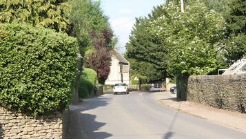 A narrow rural road flanked by stone walls and dense greenery.