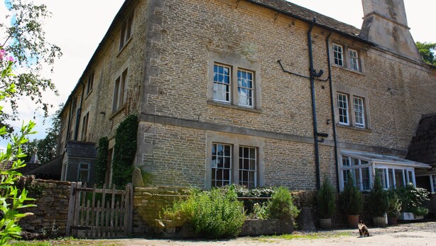 A stone building with a large window, a chimney, and a wooden fence. - Manor Farm Bed & Breakfast (Chippenham)