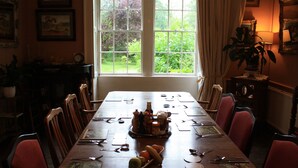 A dining room with a large table set for a meal, surrounded by chairs. - Manor Farm Bed & Breakfast (Chippenham)