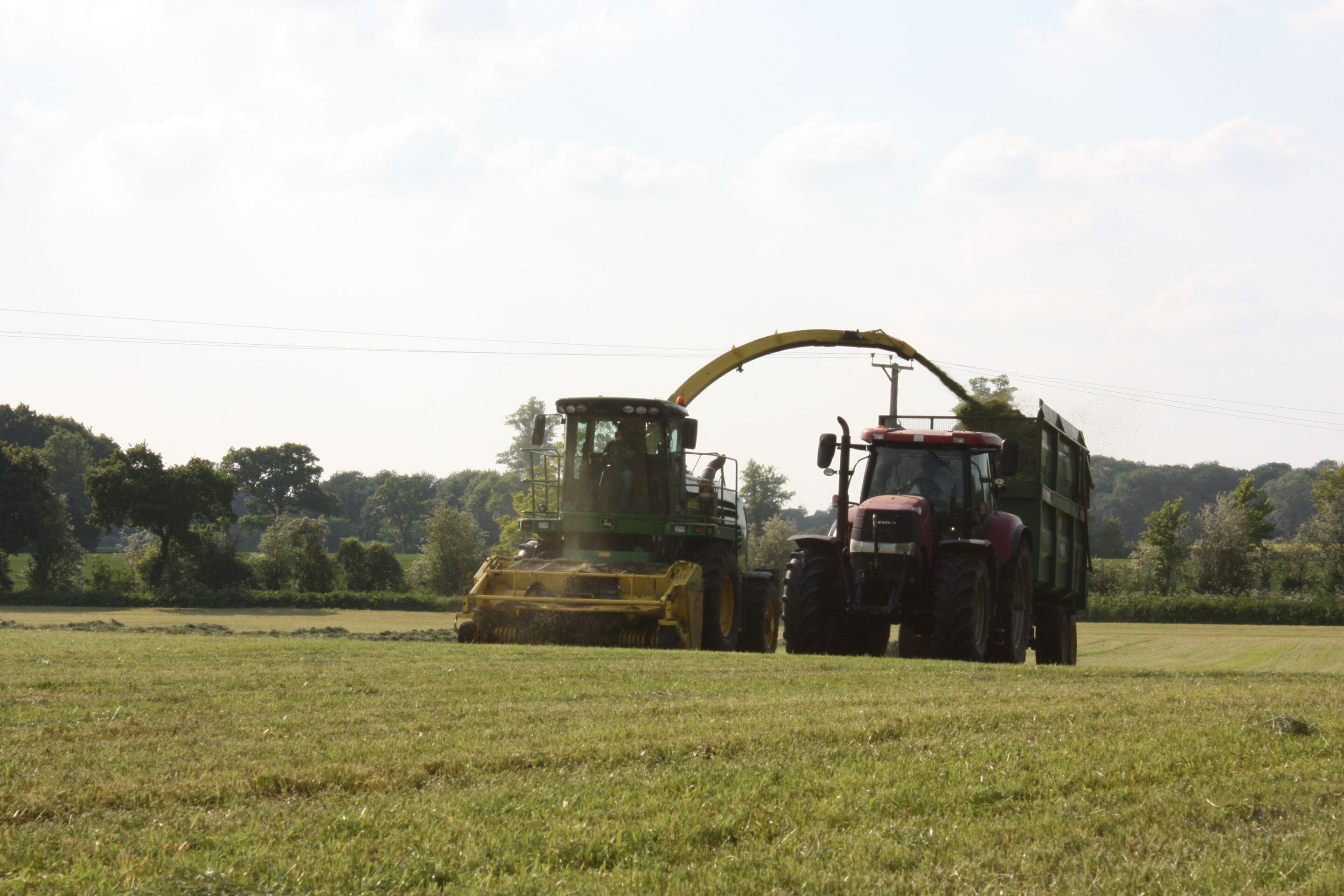 A combine harvester and tractor in a field with a clear sky.