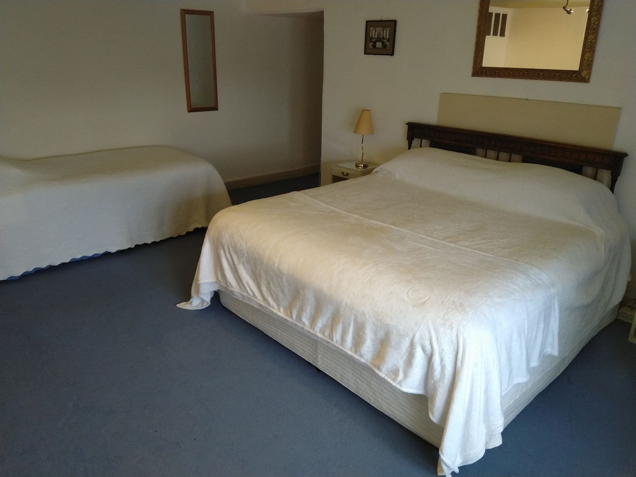 A hotel room with two single beds and a larger double bed.