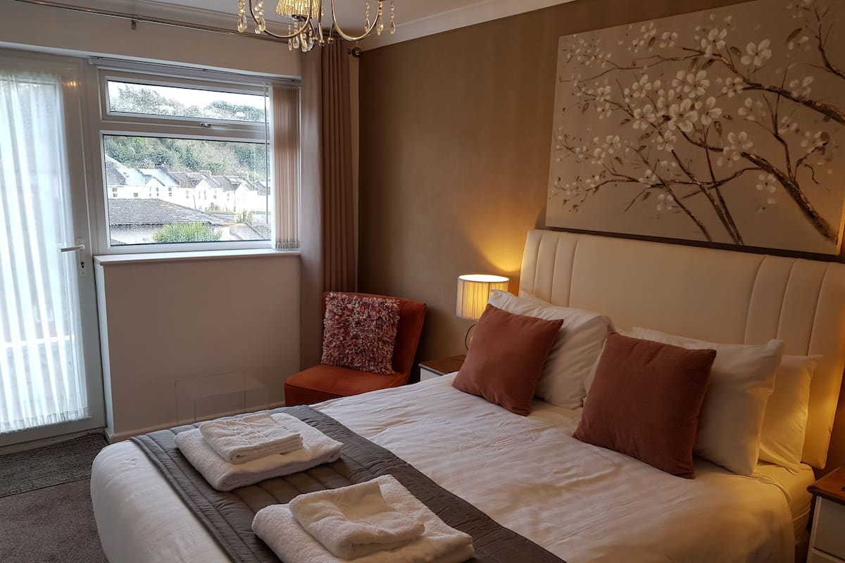 Habitación de hotel con una cama grande, una silla, una lámpara y un cuadro en la pared.