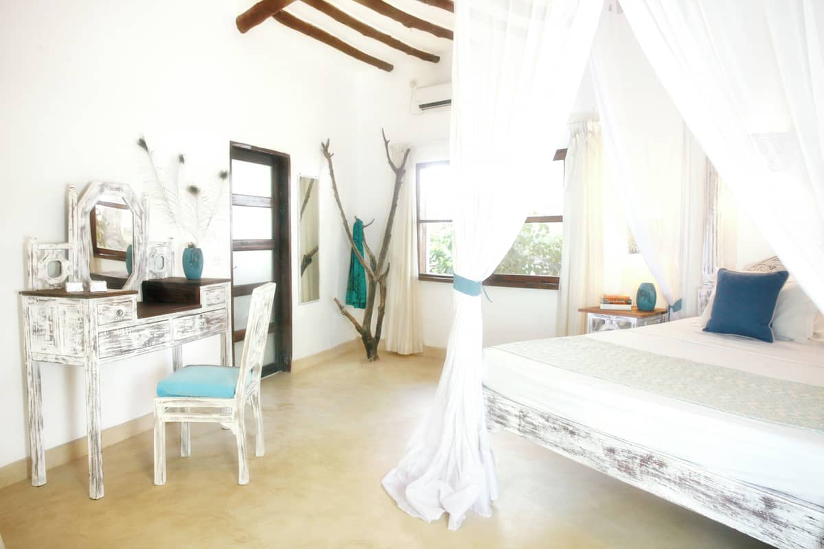 A bedroom with a bed, a desk, and a chair.