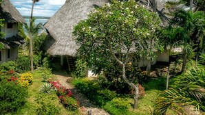 A tropical resort with thatched-roof huts, lush greenery, and a clear view of the ocean. - Temple Point Resort (Watamu)