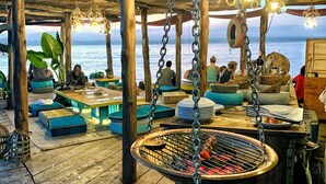 A wooden deck with seating, a hanging grill, and a view of the sea. - Temple Point Resort (Watamu)