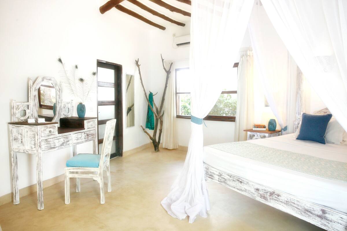 Un dormitorio con una cama, un escritorio, una silla y una ventana.