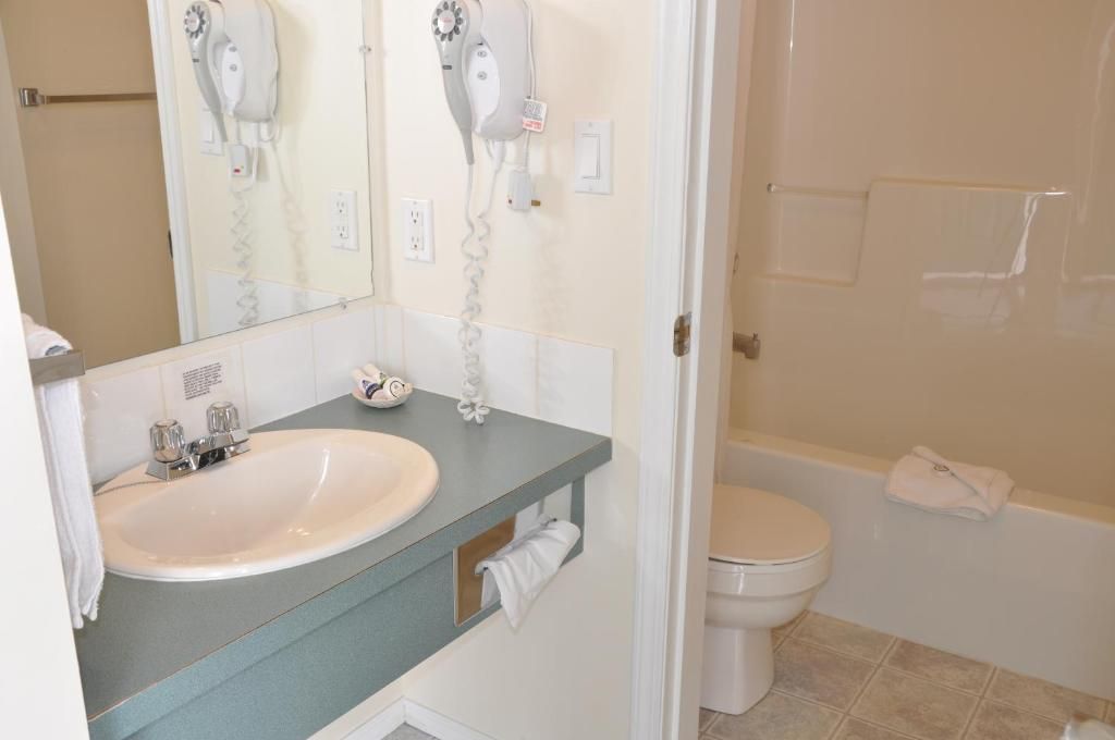 Un baño con lavabo, espejo, secador de pelo y retrete.