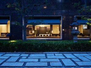 Een modern hotel met een goed verlichte entree, een receptiebalie en een zithoek zichtbaar door de ramen.