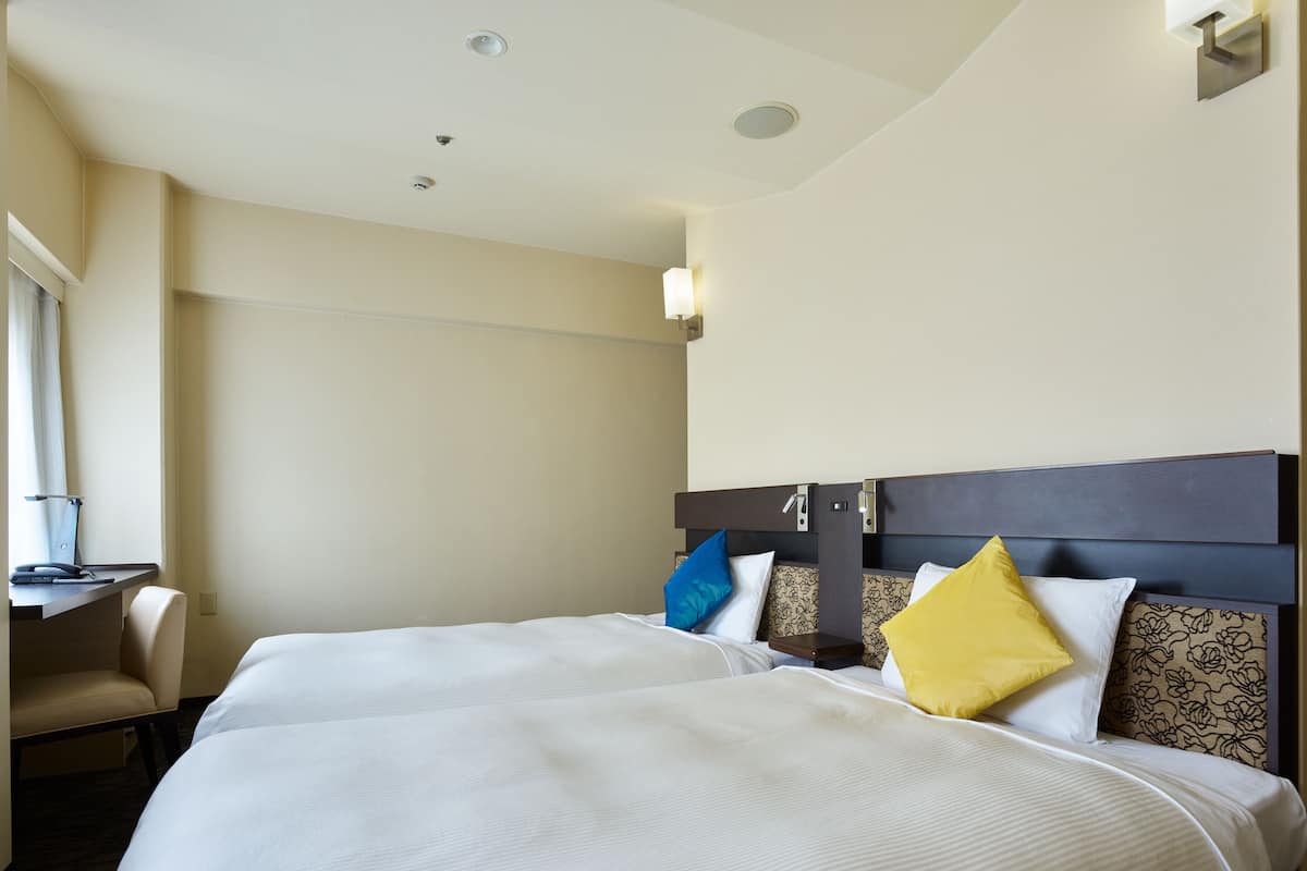 Habitación de hotel con dos camas, un escritorio y una silla.