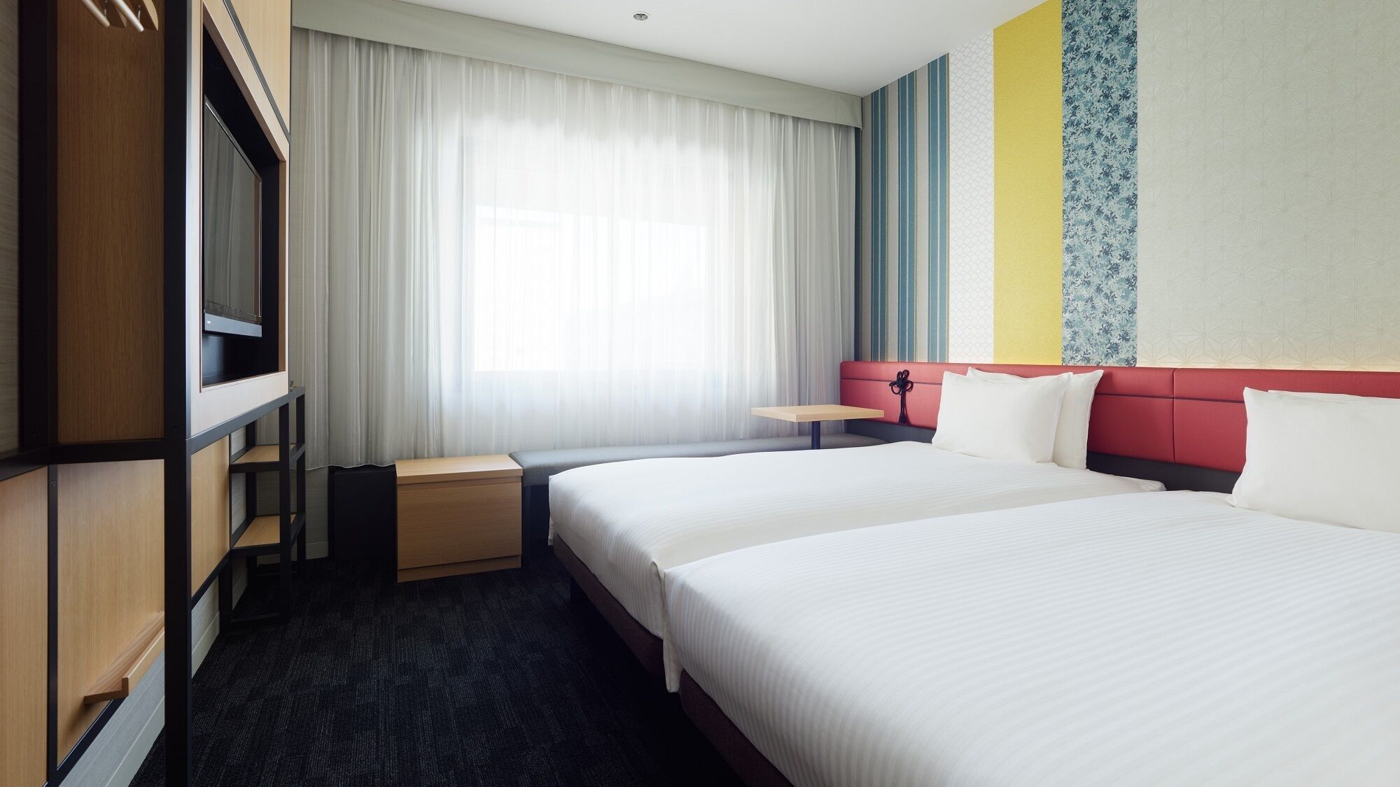 Una habitación de hotel con una cama grande, un escritorio, un armario y una ventana con cortinas.