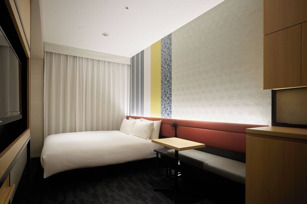 Ein Hotelzimmer mit einem Bett, einem kleinen Tisch, einer Couch und einem Fernseher.