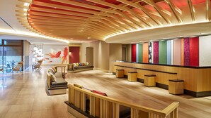 Eine moderne Lobby mit einem Holzbüro, gepolsterten Sitzgelegenheiten und einer roten Decke.