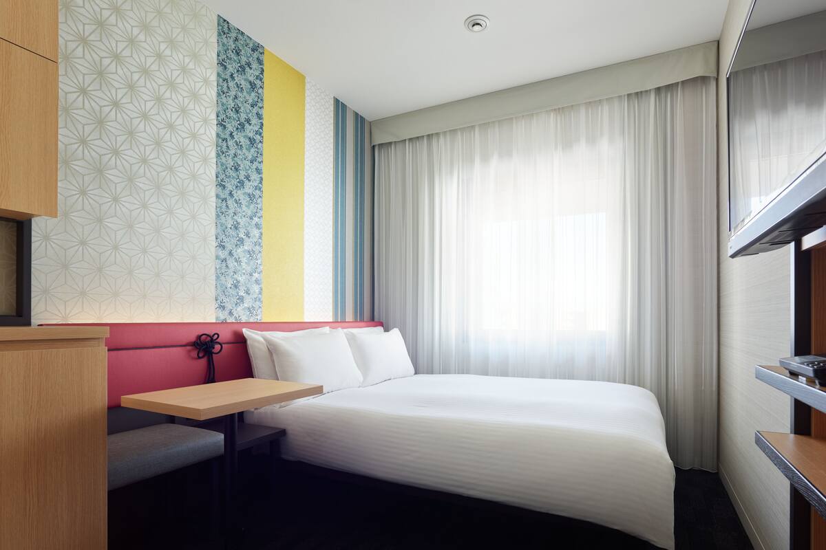 Ein Hotelzimmer mit Bett, Schreibtisch und Stuhl.