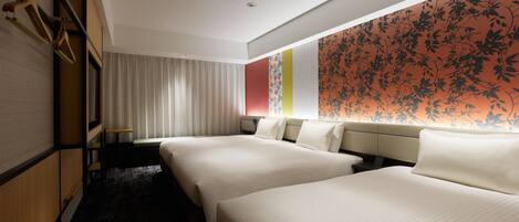 A hotel room with two beds, a large window with curtains, a wall with a floral pattern, and a wooden wardrobe.