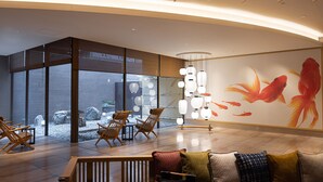 Eine moderne Lobby mit Sitzgelegenheit, großen Fenstern und einer Wandmalerei mit Koi-Karpfen.