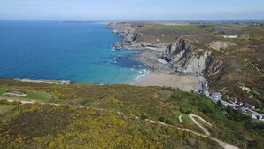 A coastal landscape with a beach, cliffs, and a small settlement with buildings. - Beacon Country House Hotel (St. Agnes)