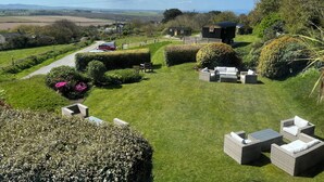 A well-maintained garden with neatly trimmed hedges, outdoor seating, and a view of the countryside. - Beacon Country House Hotel (St. Agnes)