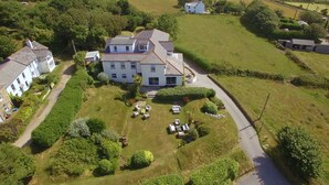 An aerial view of a large, two-story house with a spacious lawn, multiple outdoor seating areas, and a well-maintained garden. - Beacon Country House Hotel (St. Agnes)