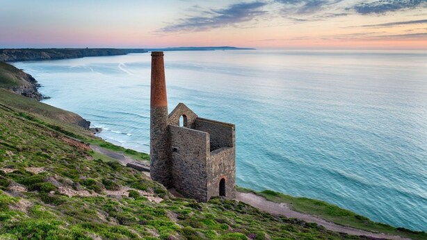 A coastal lighthouse structure with a tall chimney, situated on a grassy cliff overlooking the sea. - Beacon Country House Hotel (St. Agnes)