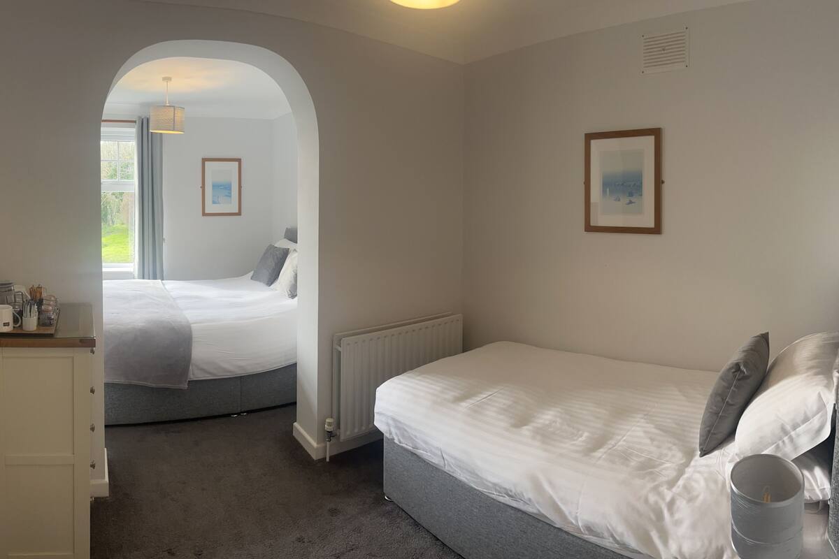 A bedroom with a bed, a radiator, a desk, and a window.