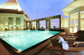 A rooftop infinity pool with lounge chairs and a view of the city skyline.
