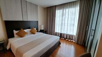 Una habitación de hotel con una cama grande, una mesita de noche, una silla y una ventana con cortinas.