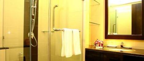 A modern bathroom with a glass-enclosed shower, a sink with a mirror, and a towel rack.