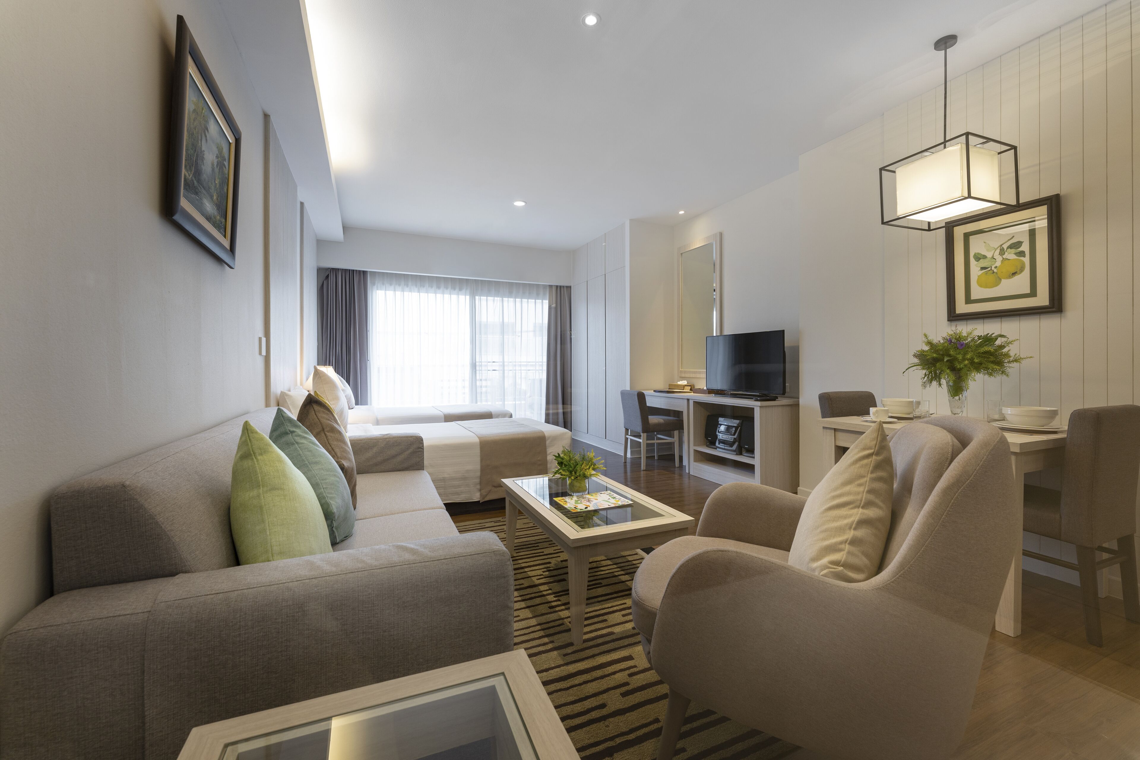 A modern living room with a sofa, armchair, coffee table, and a TV. There is a dining area with a table and chairs.