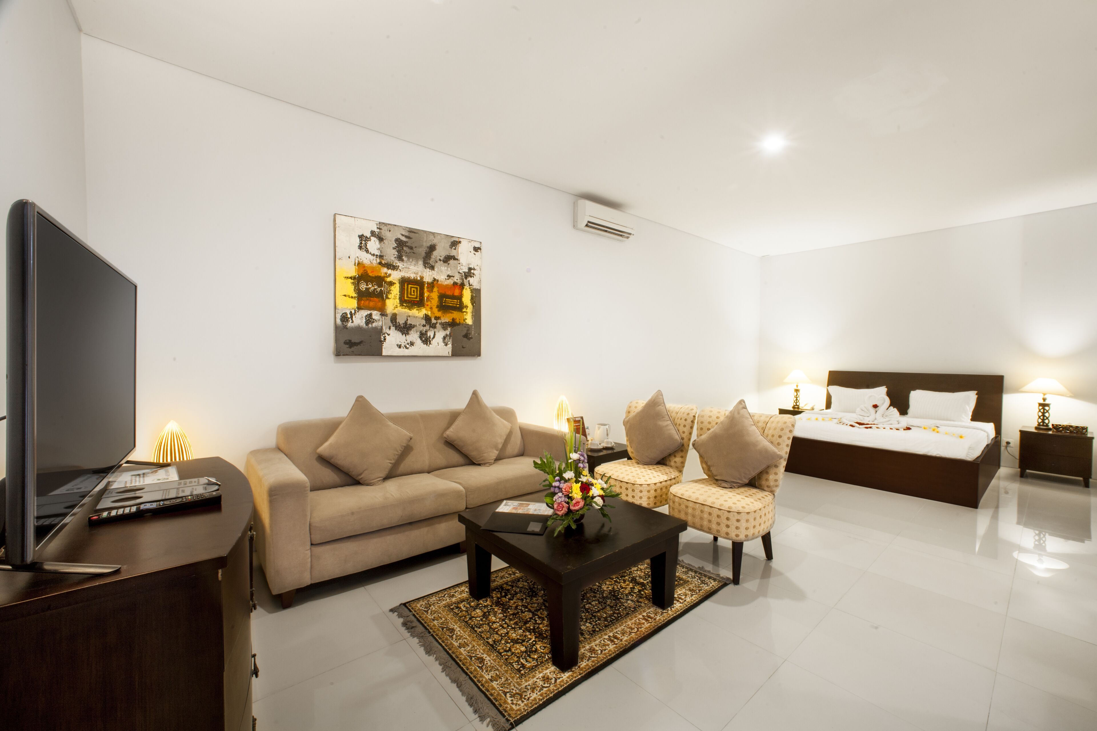 A modern living room with a sofa, a coffee table, a TV, and a bed with a headboard.