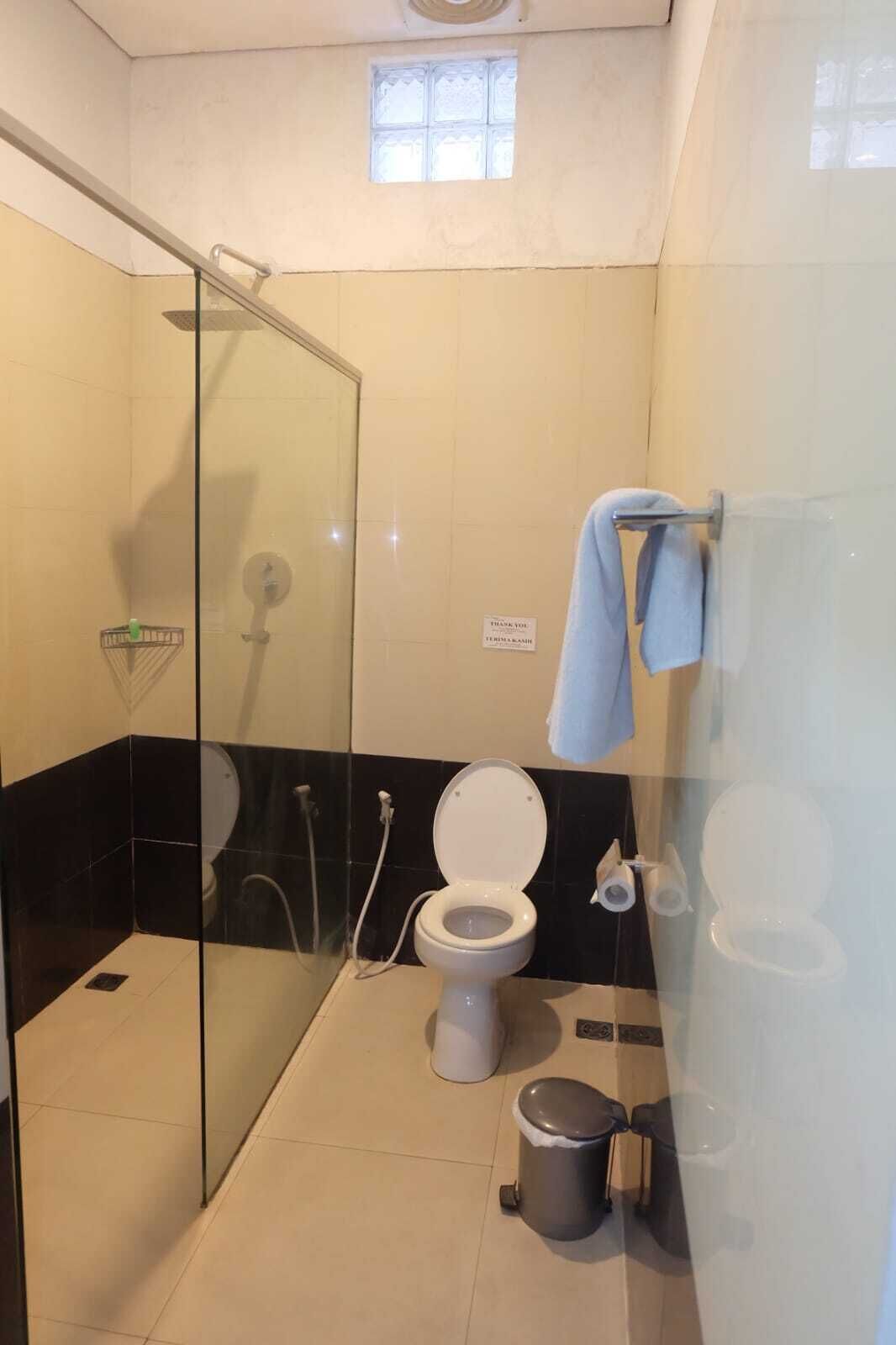 Un baño con cabina de ducha de vidrio, inodoro, bidé y un cubo de basura.