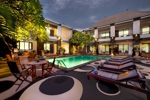 A poolside area with lounge chairs, a table, and a pool. - The Radiant Hotel (Tuban)
